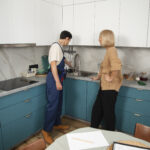 male-plumber-working-with-client-fix-kitchen-problems